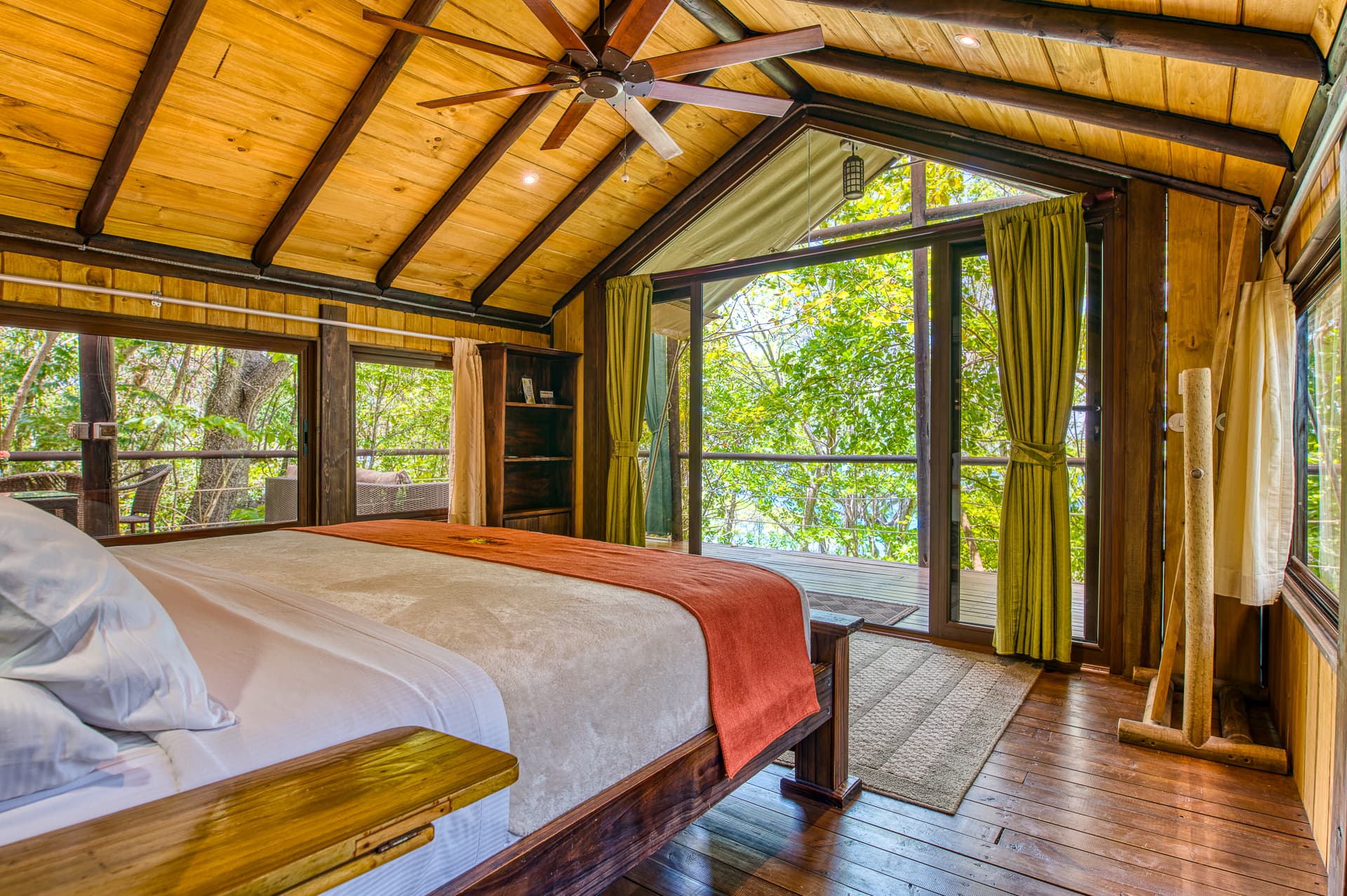 Interior of honeymoon suite with king bed, vaulted ceilings with ceiling fan, and glass doors leading to open-air patio
