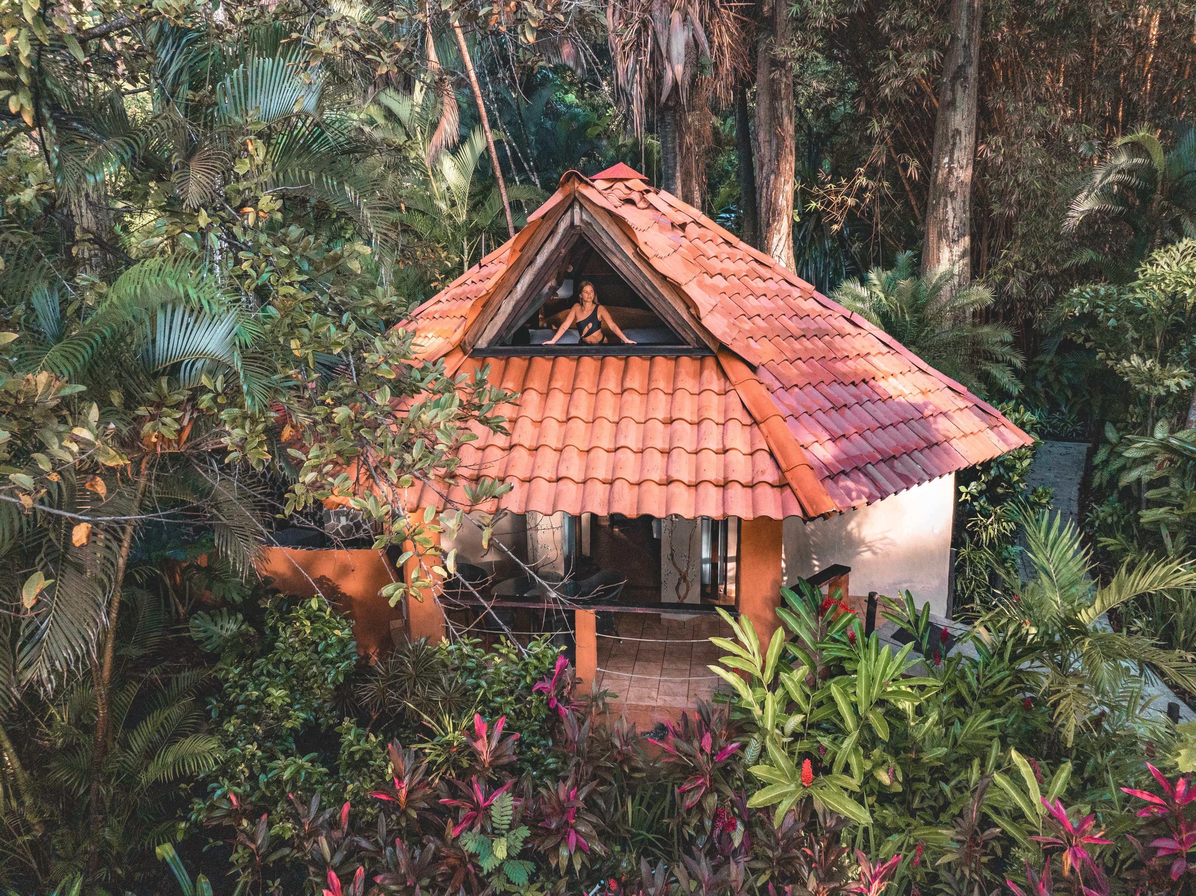 Main floor of bungalow with brightly adorned bed, steps going up to loft, and sliding doors to private patio