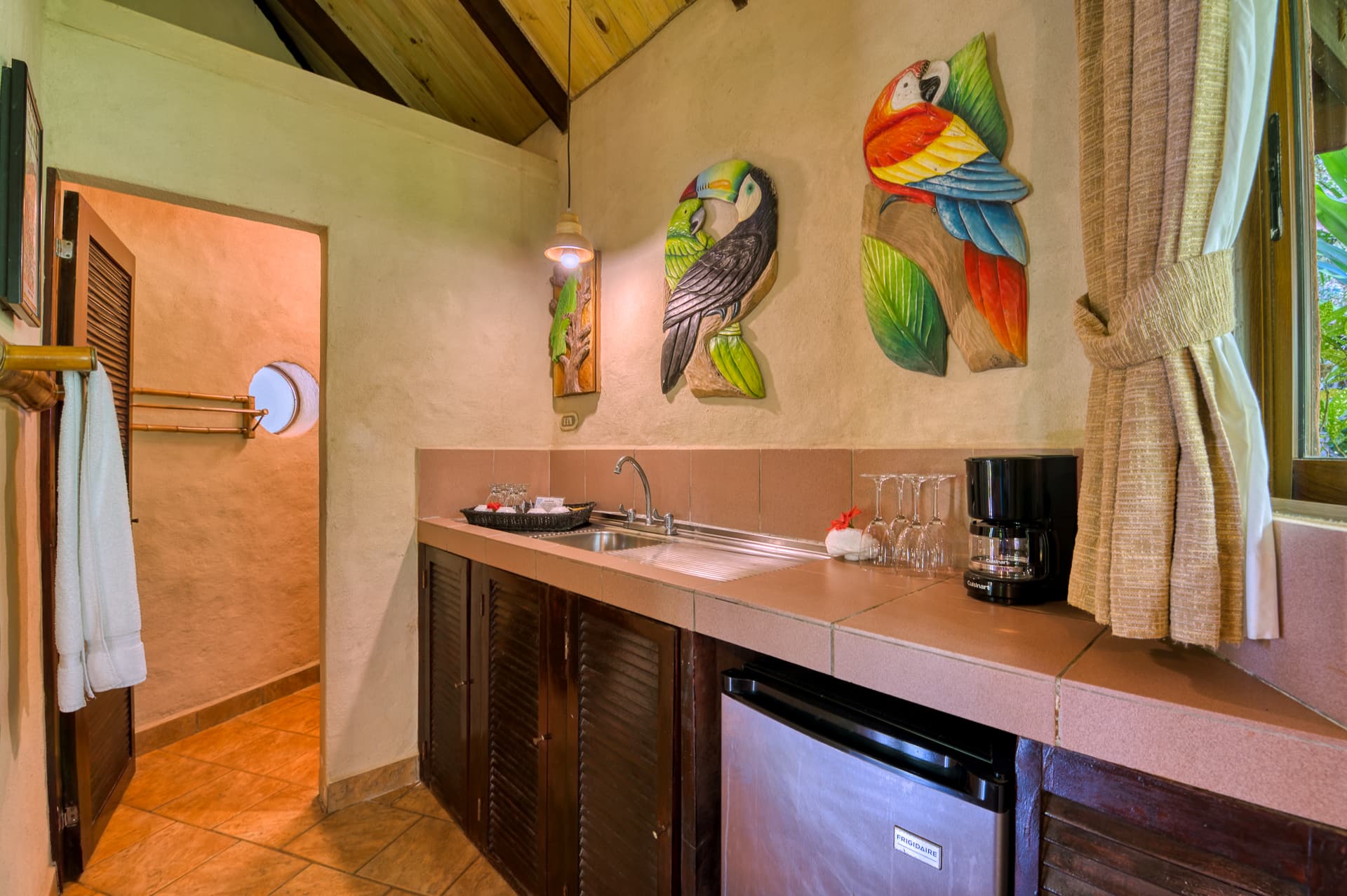 Kitchenette area with counter, coffee maker and mini refrigerator, doorway leading to bathroom