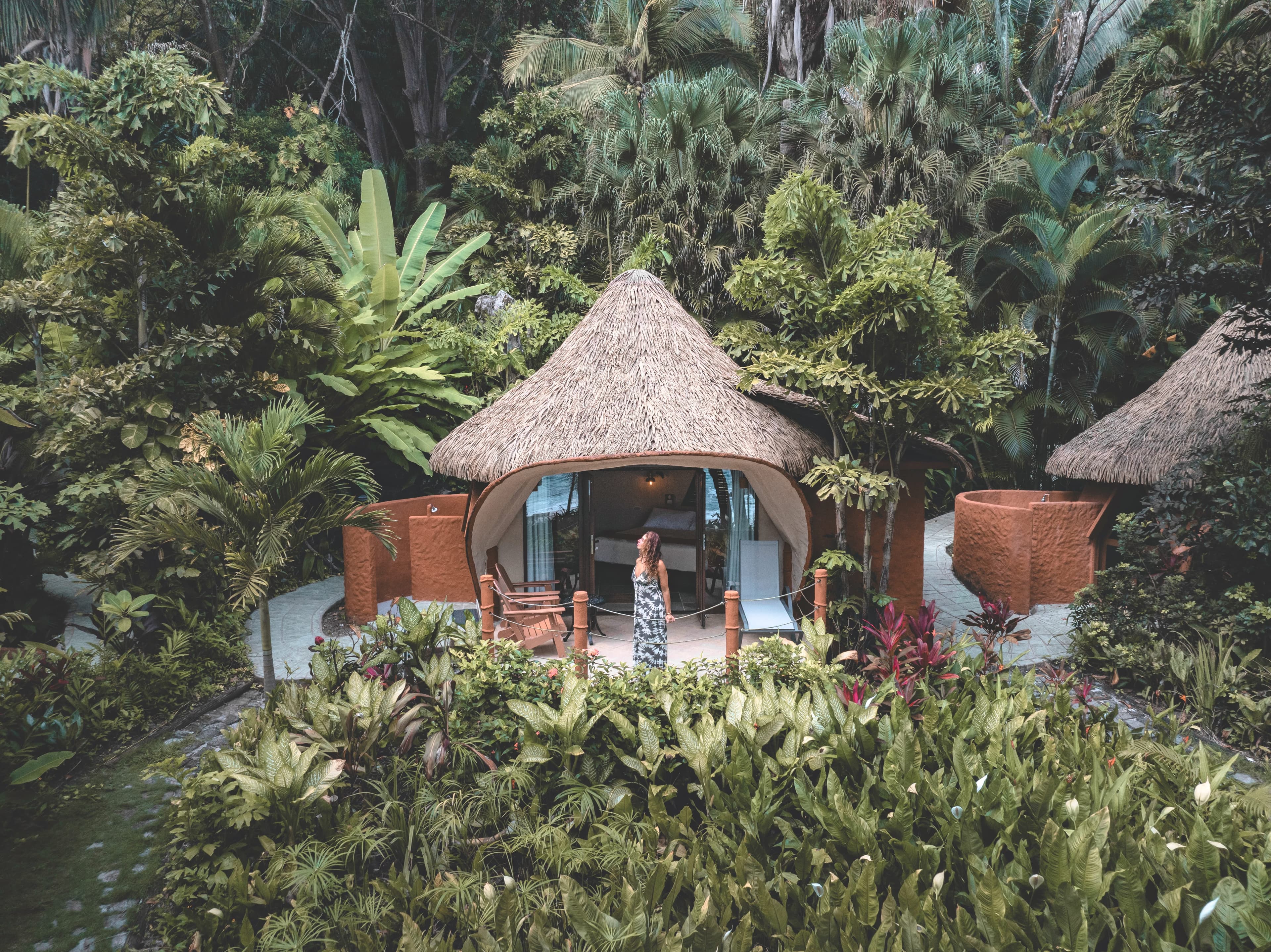 Beachfront bungalow bedroom in tranquil neutral colors, platform bed, and ylang ylang tree painted on wall
