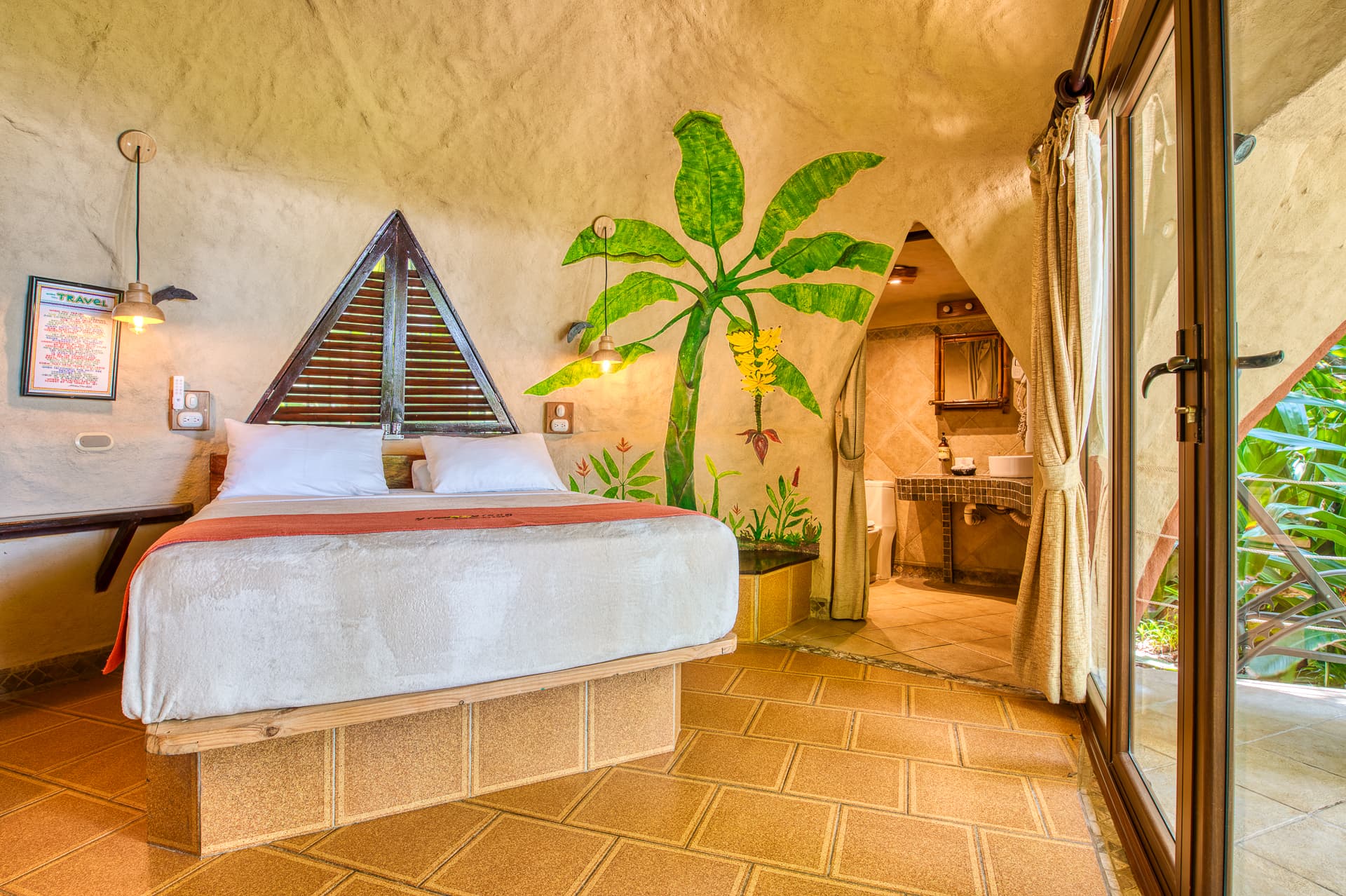 Beachfront bungalow bedroom in tranquil neutral colors, platform bed, and ylang ylang tree painted on wall