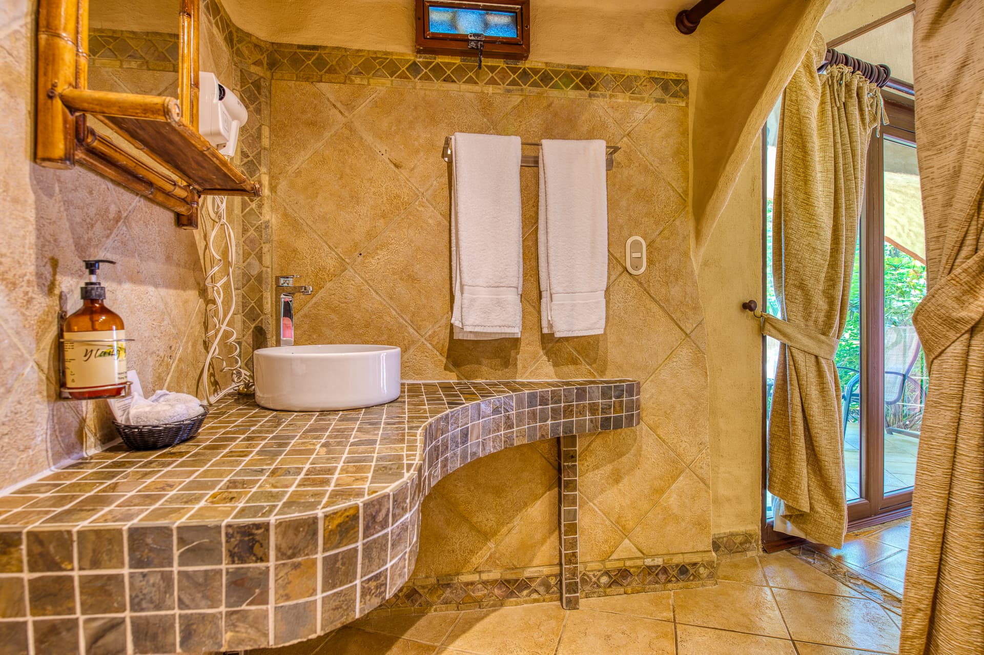 Beach bungalow bathroom with curved, tiled vanity with vessel sink, and doorway leading to main room