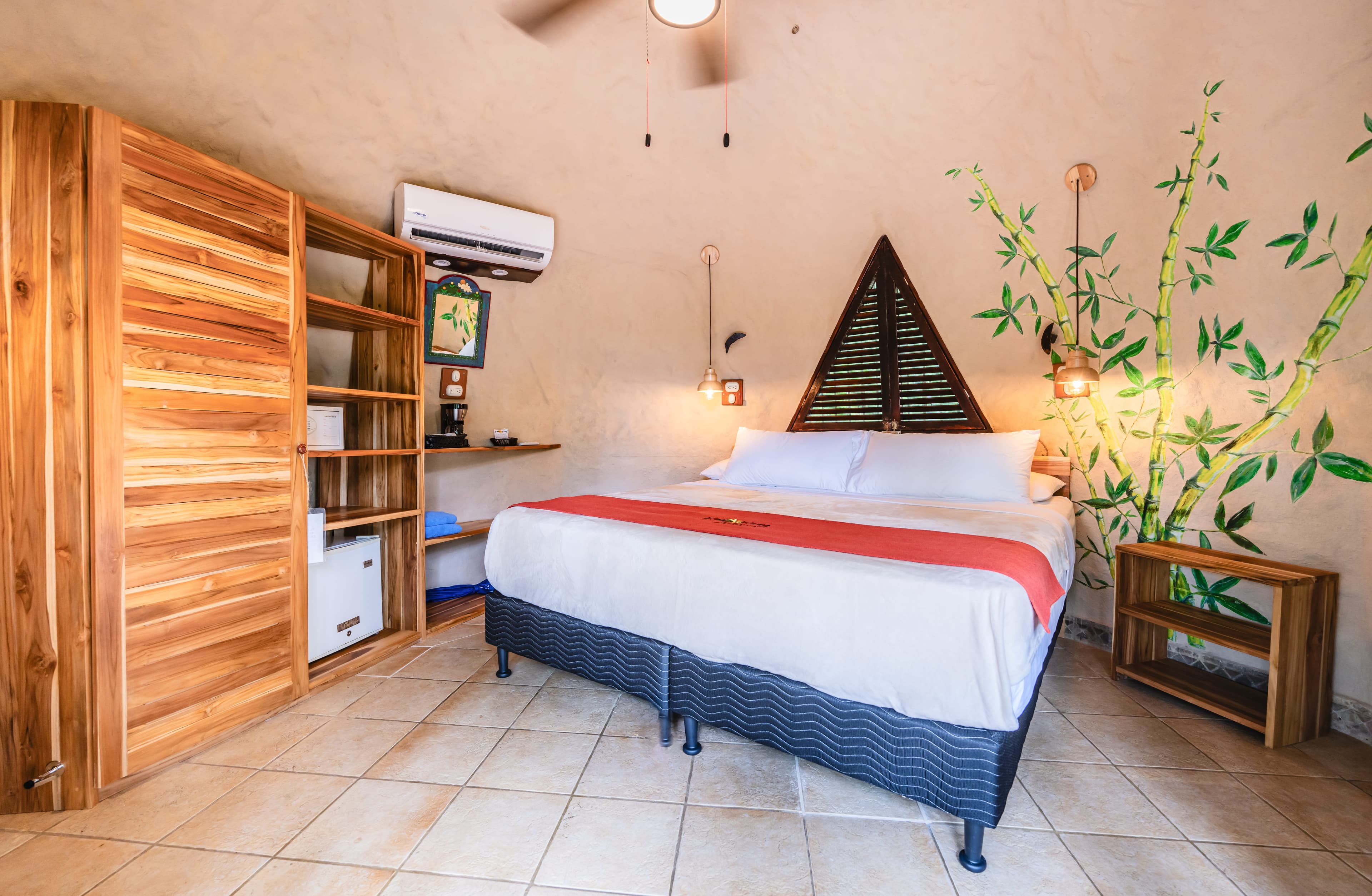 Bedroom at Garden Bungalow decorated in warm, neutral tones, platform bed, and ylang ylang tree painted on the wall