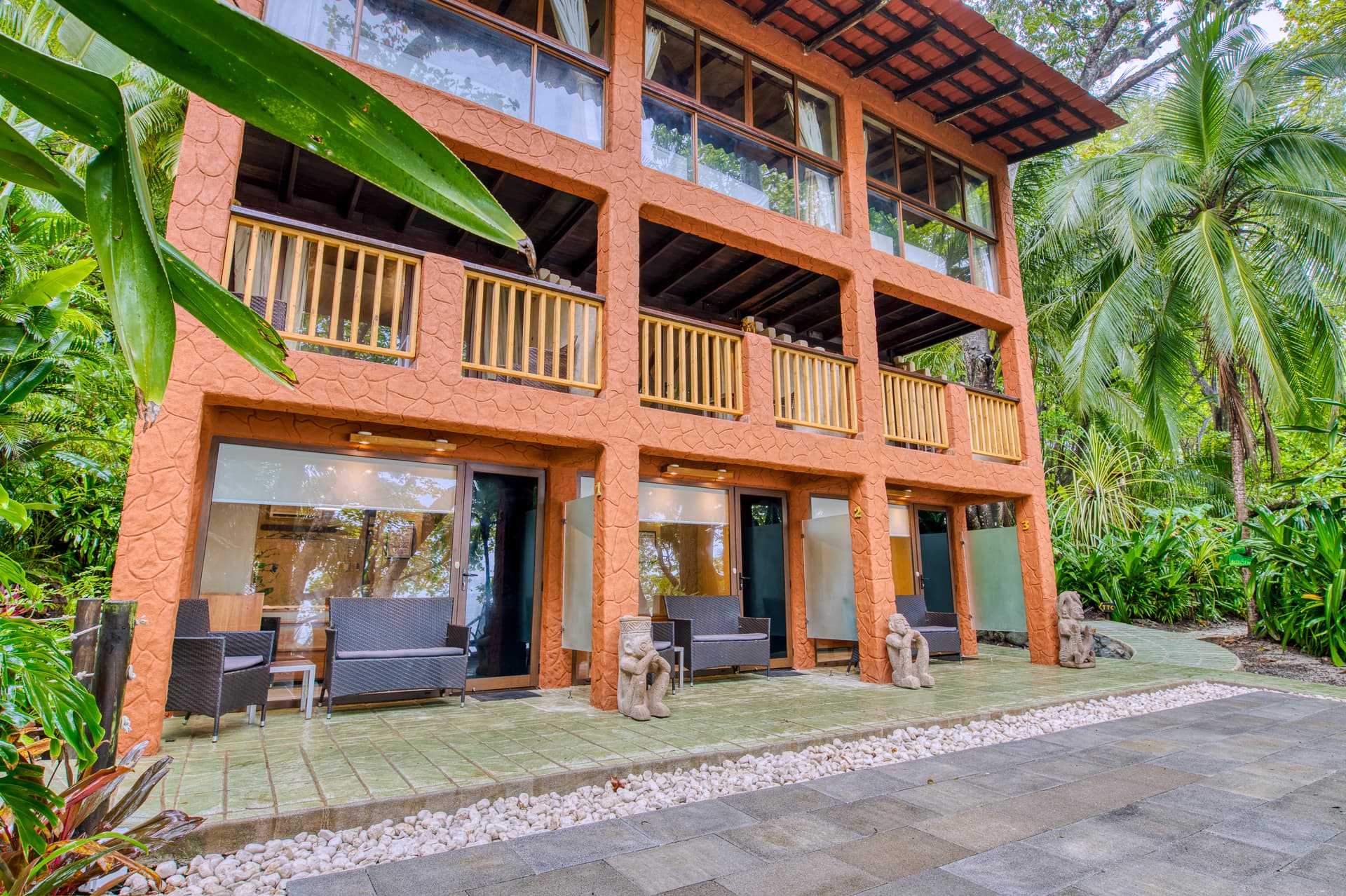 Exterior view of hotel with outdoor patios and balconies, surrounded by tropical foliage