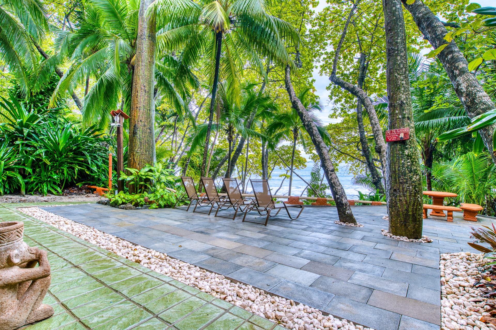 Terrace at resort with chairs and tables and surrounded by lush tropical foliage