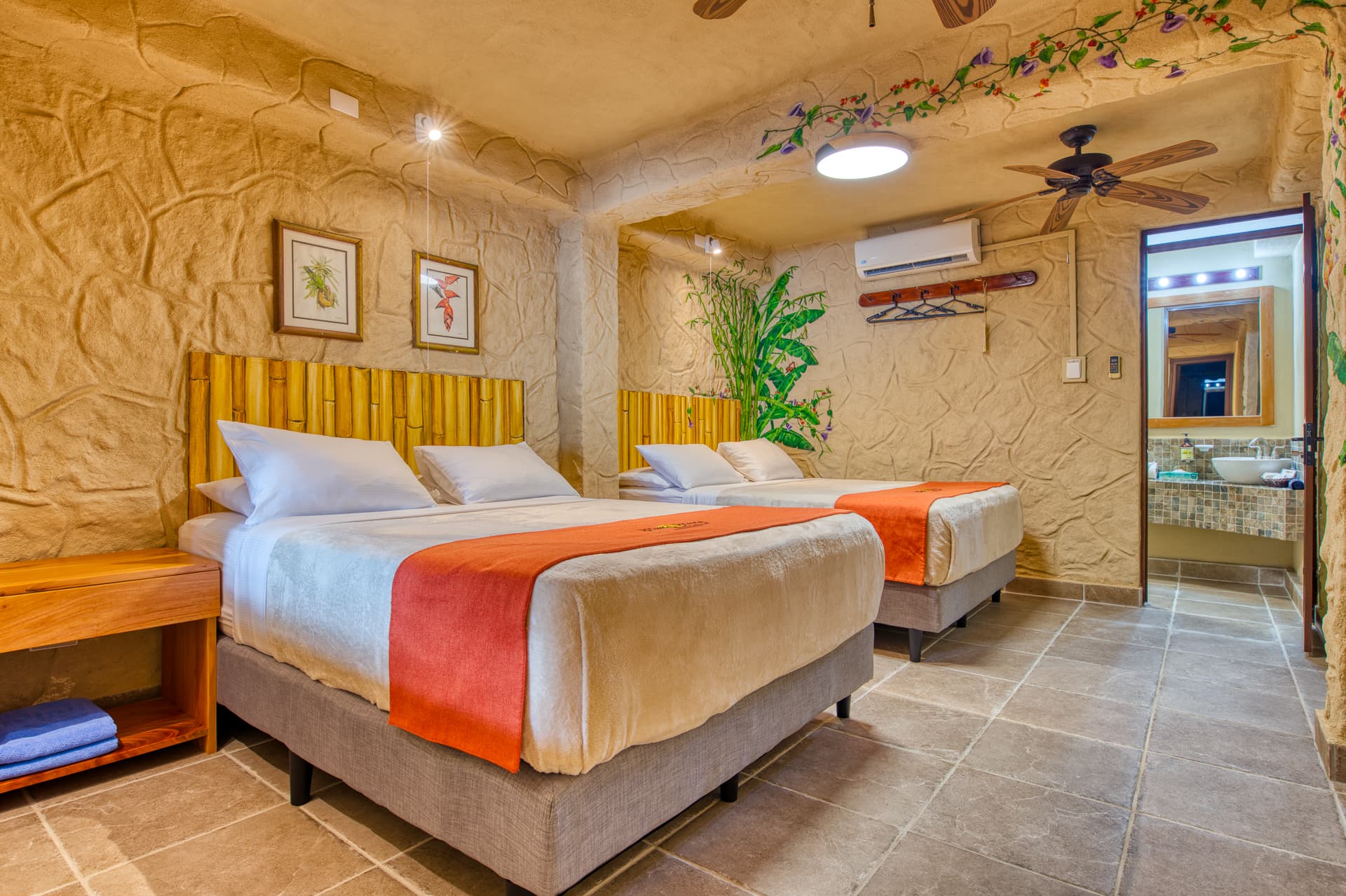 Ground-floor room with two queen platform beds, ceiling fans, and doorway to private bath
