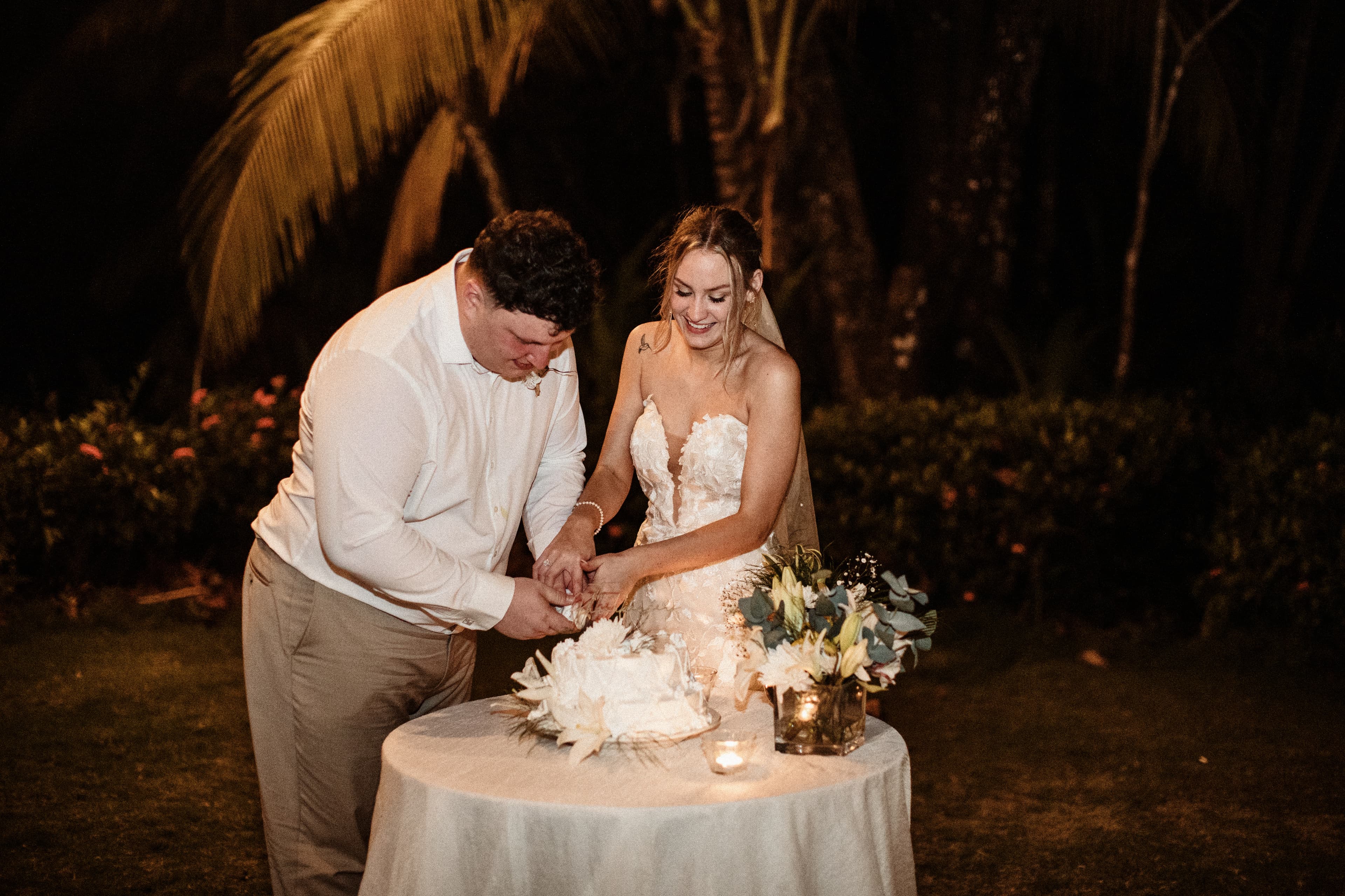 Outdoor nighttime scene of a bride and groom cutting a wedding cake