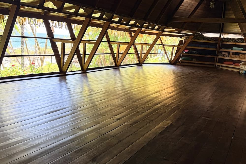 A spacious wooden room with large windows showcasing tropical scenery.