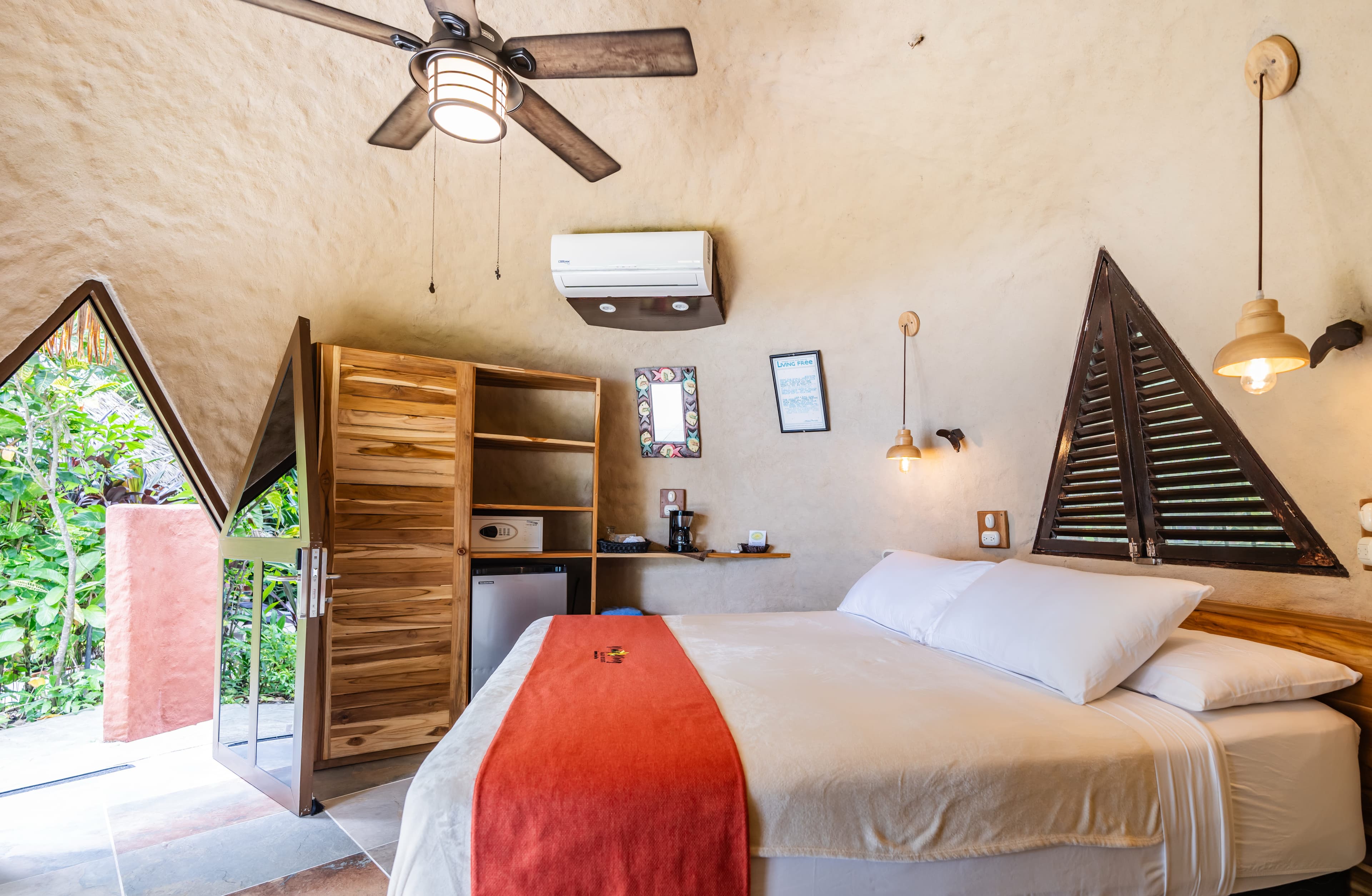 A cozy bedroom with a queen-sized bed, wooden furniture, and unique triangular windows.