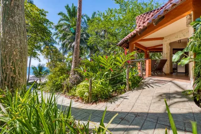 Lush tropical garden leads to a cozy patio overlooking the ocean.