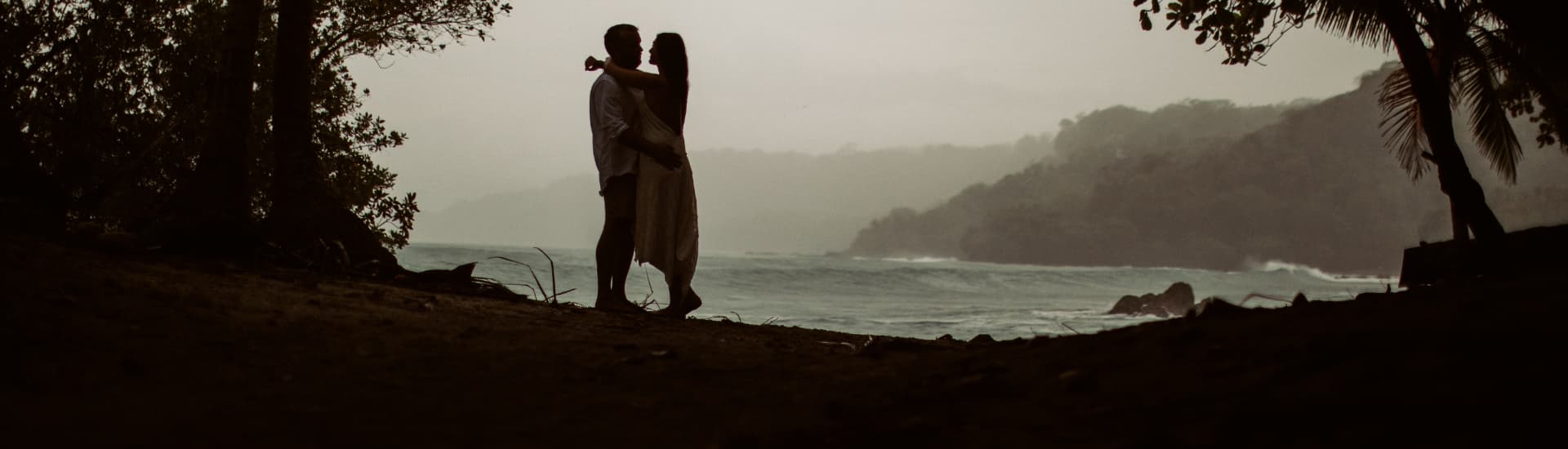 Embracing couple silhouetted against misty sky overlooking the ocean
