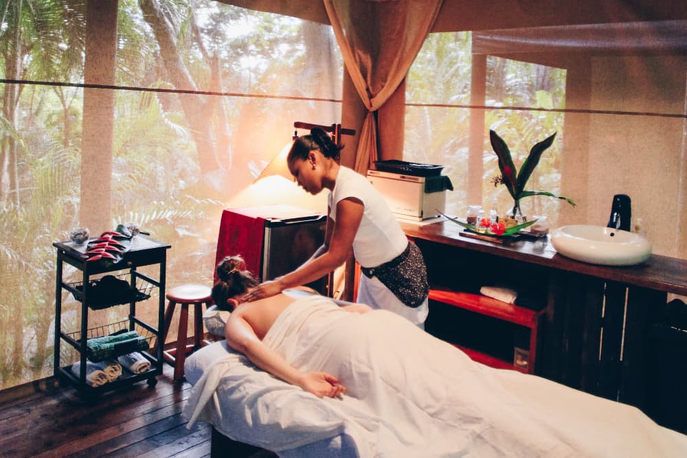 A woman lying face down on a massage table having her neck massaged