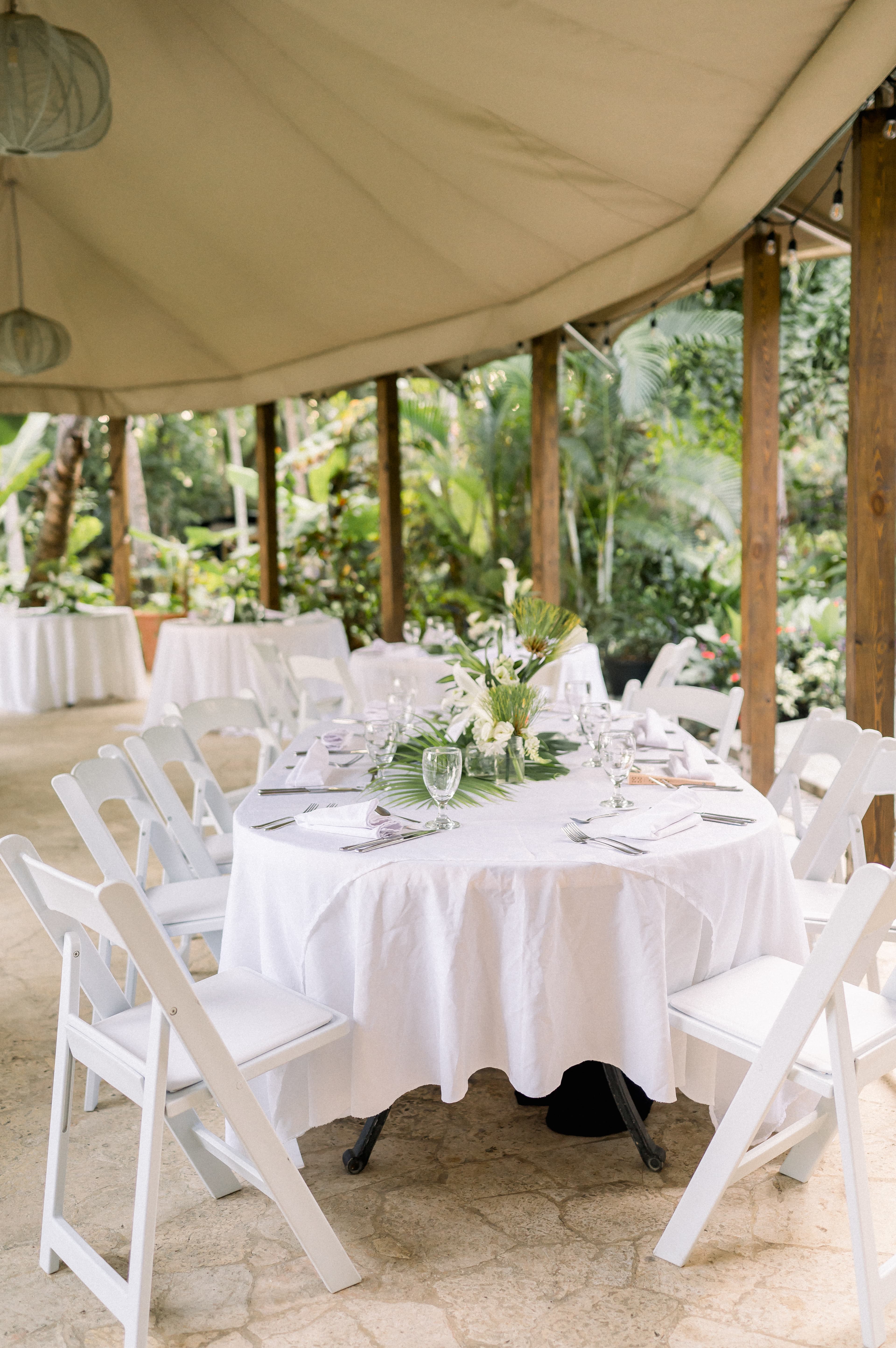 Reception table with place settings and white tablecloths and white wood chair