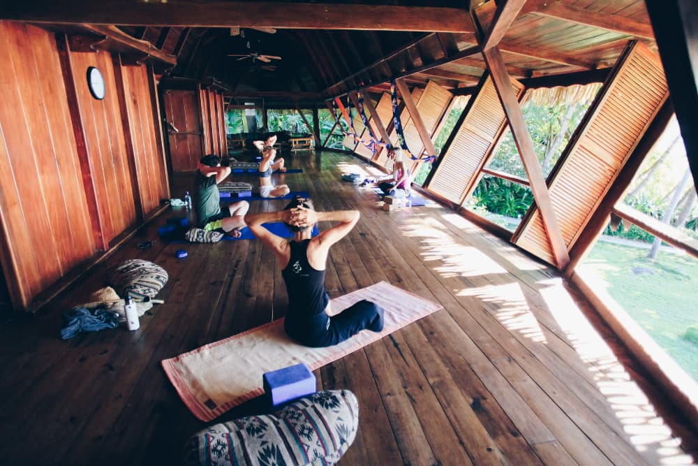 A small group of people sitting on yoga mats with their hands clasped behind their heads