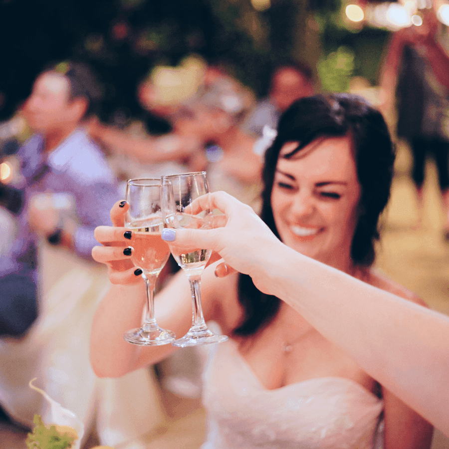 A bride joyfully toasts with sparkling drinks at a celebratory gathering.