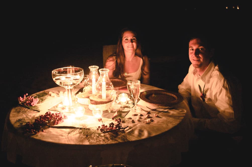 Smiling couple seated at a candlelit table at night