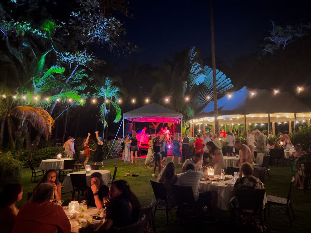Nighttime scene of live band performing while people seated at candlelit tables watch & listen