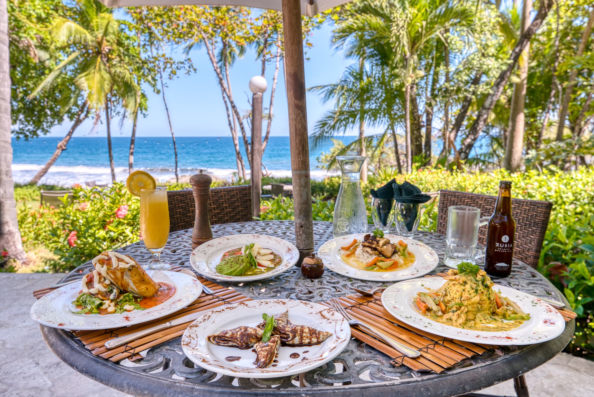 Table set with plates of food outdoors with view of ocean and