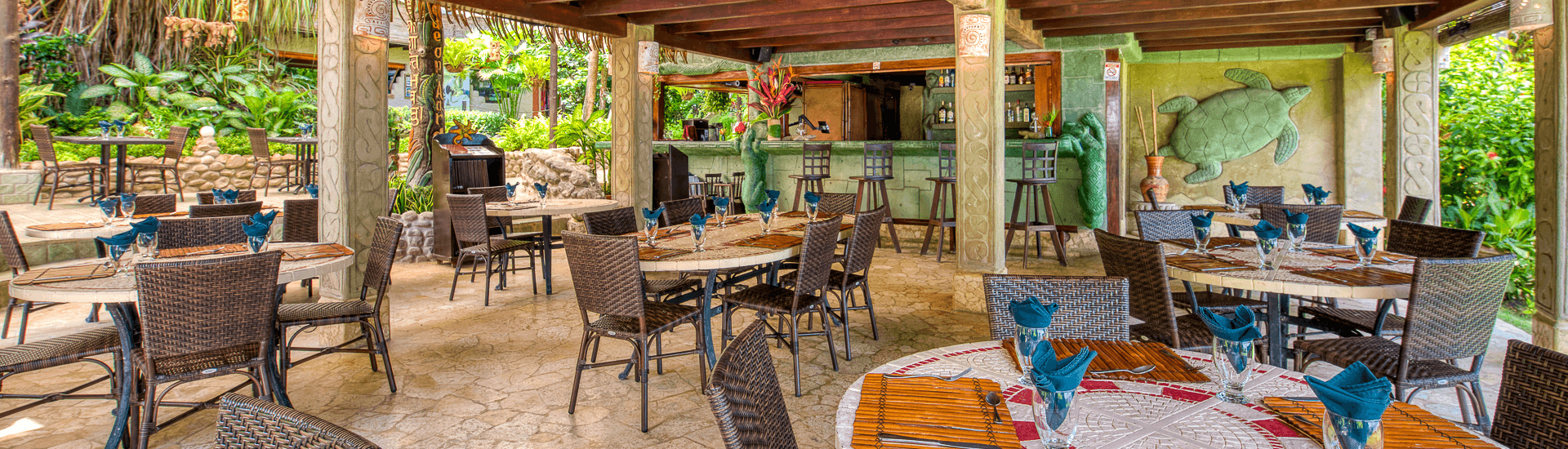 Outdoor dining area, stone floor, bar, wood ceilling, round tables and wicker style chairs