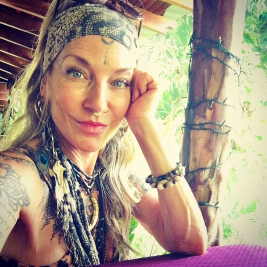 Woman with bright blue eyes and wavy blond hair pulled back in a bandeau headband and resting her cheek on her hand