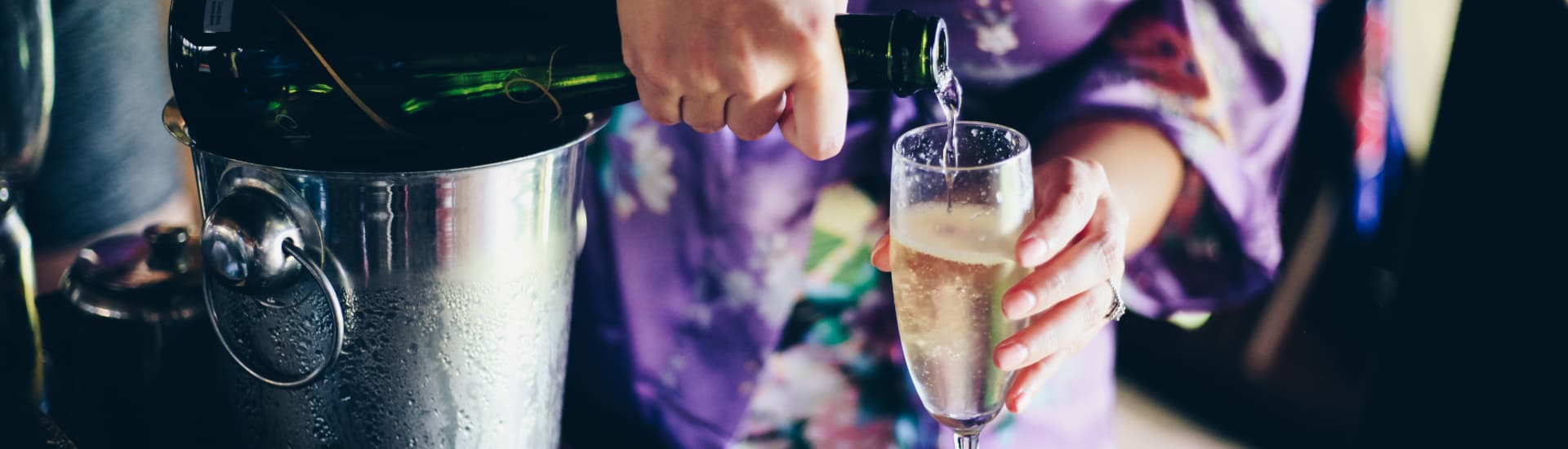 Champagne being poured from a green glass bottle into a clear flute glass