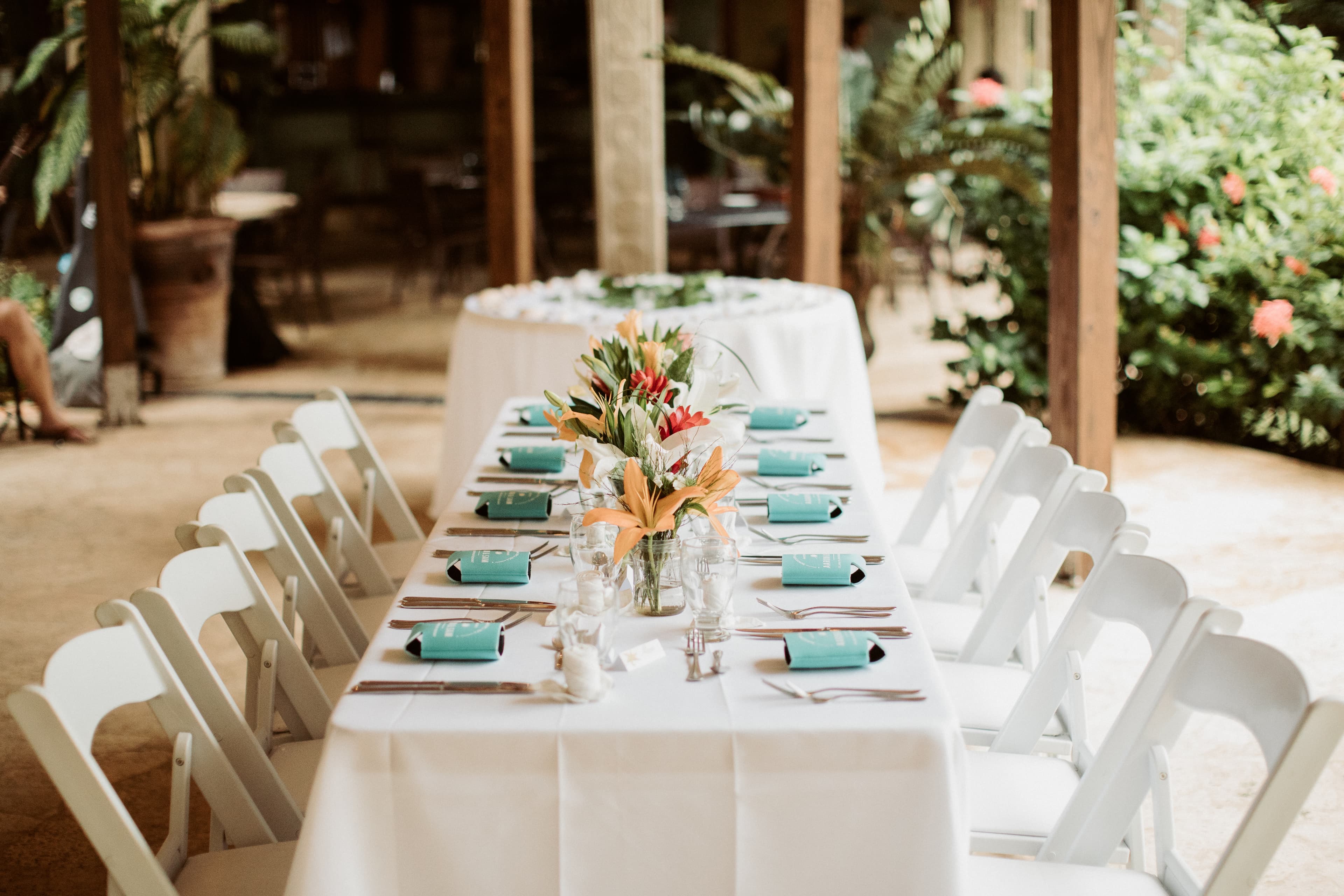 Reception table with place settings and white tablecloths and white wood chair