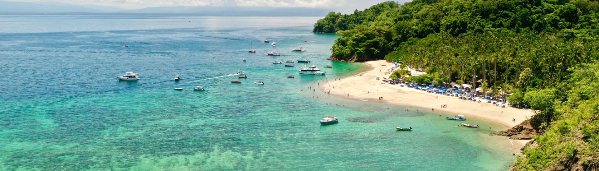 Beautiful bird's eye view of a brilliant blue ocean, sandy beach, and tropical foliage