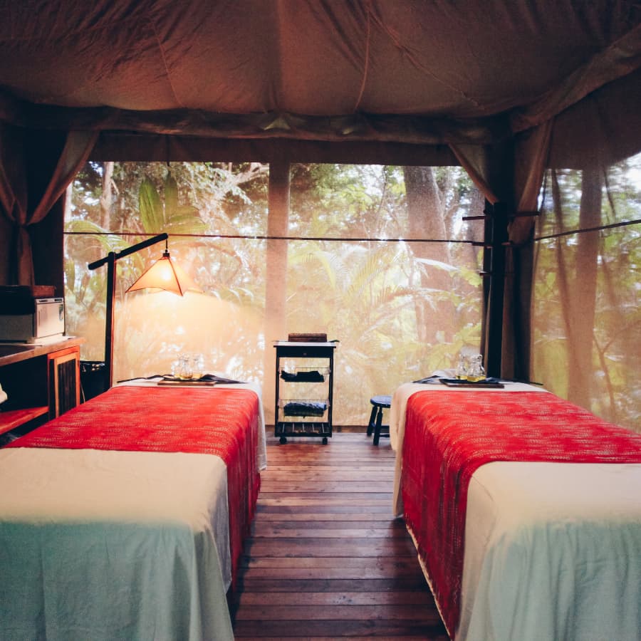 Screened-in jungle cabana with hardwood floors and two massage tables set up side-by-side