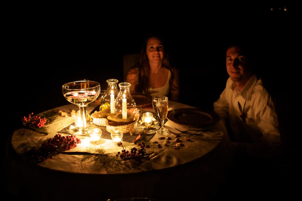 night photo of dining on beach with man and woman in candlelight