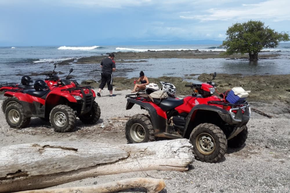 two red atv 4x4s on beach with 2 people near water