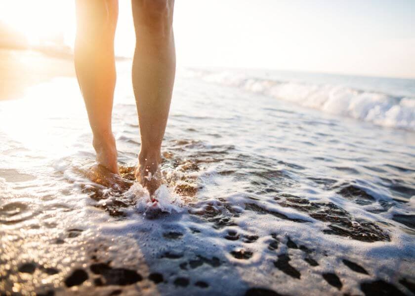 Bare feet wading through gentle ocean waves at sunset. Bare feet wading through gentle ocean waves at sunset.