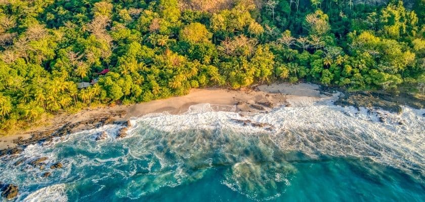 aerial view of a secluded costa rica beach with turquoise waves and lush green rainforest